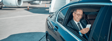A man enjoying a comfortable airport transfer service in the backseat of a premium chauffeur-driven car.