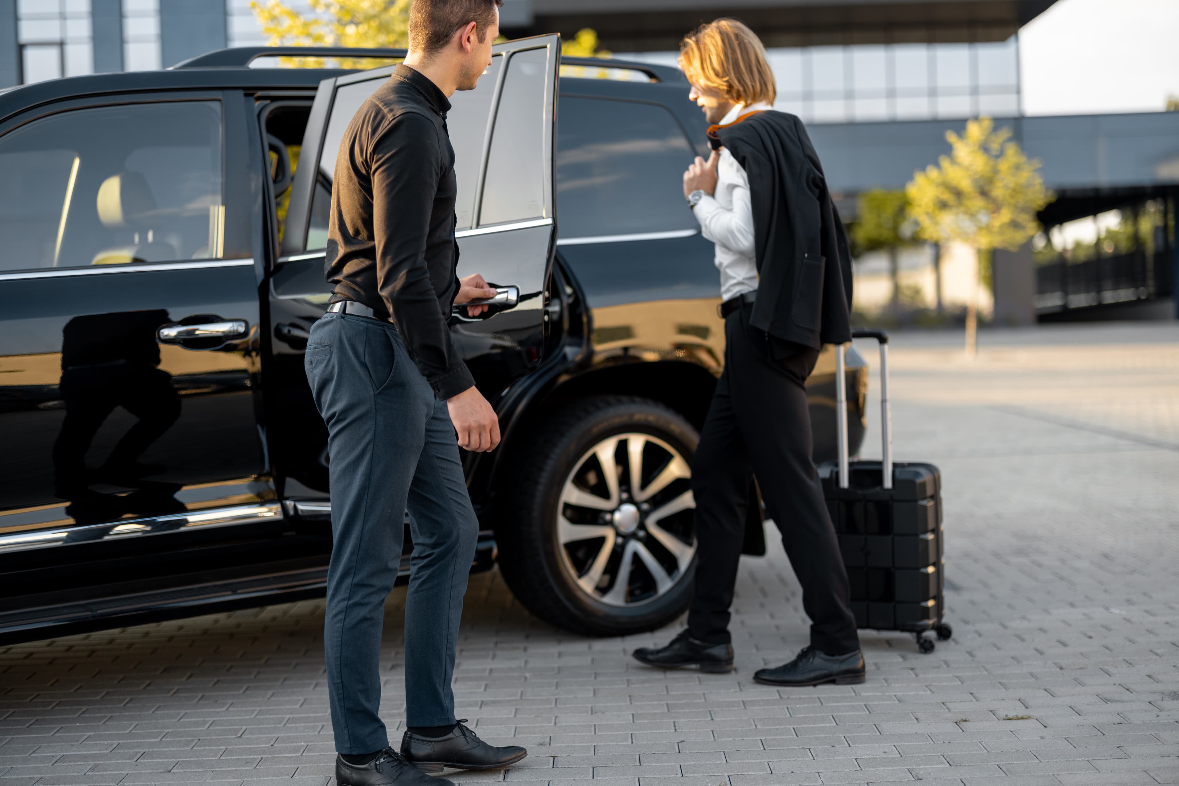 A client using an hourly hire chauffeur service, with the driver opening the car door for her.